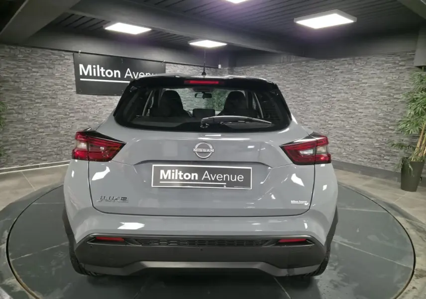 Vue arrière d'un Nissan Juke gris métallisé 2023 avec feux LED et toit noir en showroom.
