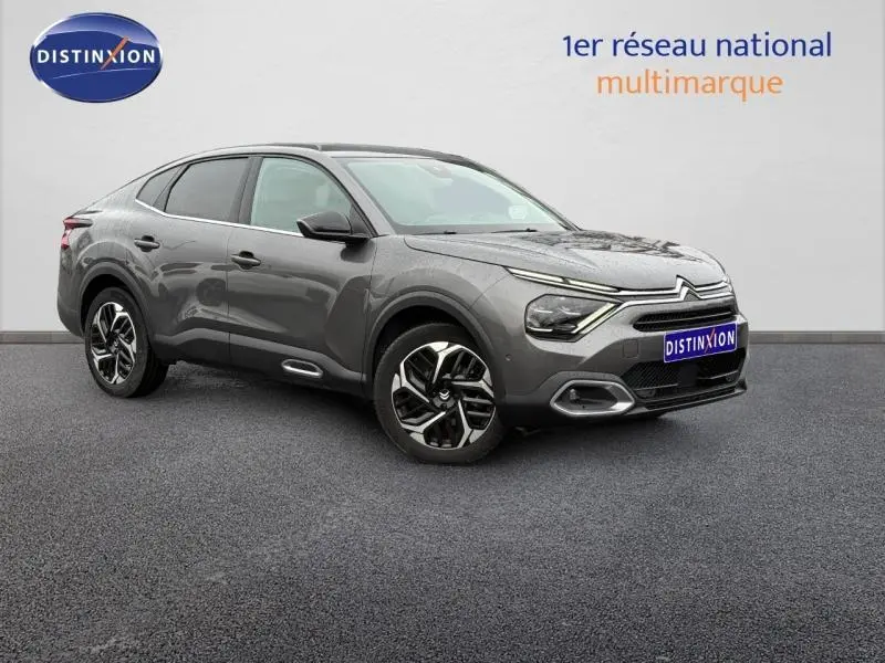 Citroën C4 X gris 3/4 avant droit, avec signature lumineuse distinctive et jantes alliage bicolores.