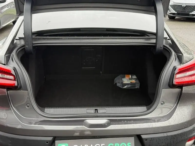 Coffre ouvert vu de l'arrière d'une Citroën C4 X gris 2024, avec un petit objet posé à l'intérieur.