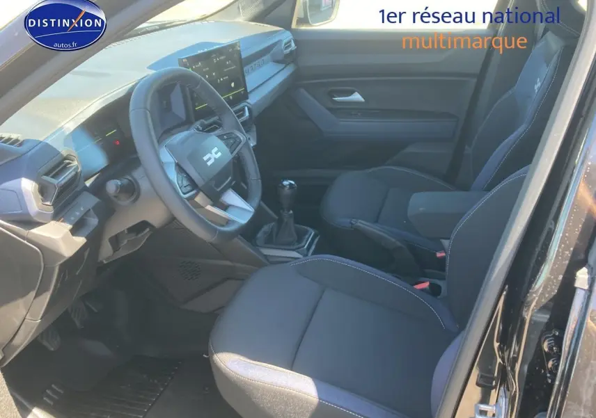 Intérieur noir du Dacia Duster 2025 vu côté conducteur, avec volant multifonction et boîte manuelle.