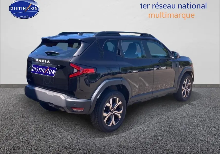 Vue 3/4 arrière droite d'un Dacia Duster noir 2025 avec barres de toit et jantes alu distinctives.