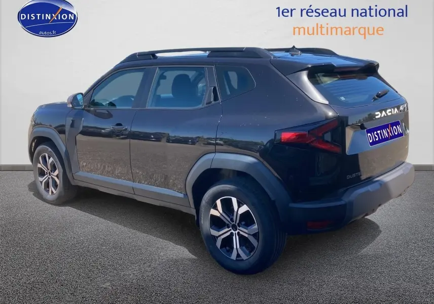 Vue 3/4 arrière droite du Dacia Duster noir 2025 avec jantes alu et barres de toit visibles.