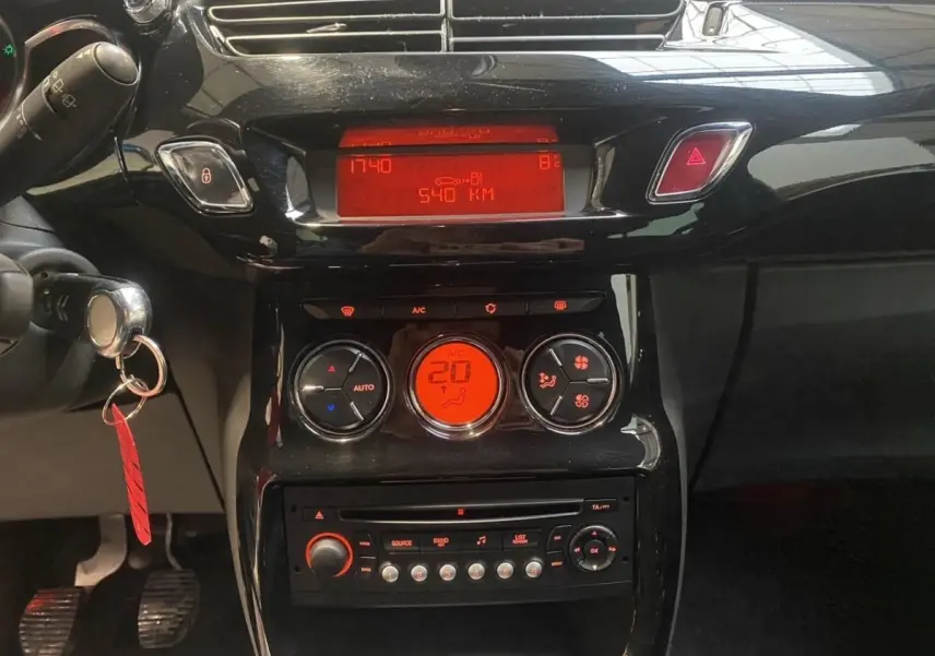 Vue rapprochée du tableau de bord noir brillant de la Citroën DS3 e-HDi, avec affichage digital rouge et commandes climatisation.