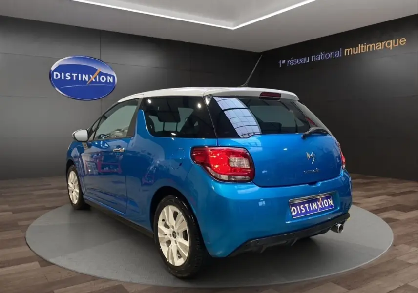 Vue 3/4 arrière droite d'une Citroën DS3 e-HDi 90 Airdream So Chic bleu avec toit blanc et jantes blanches.