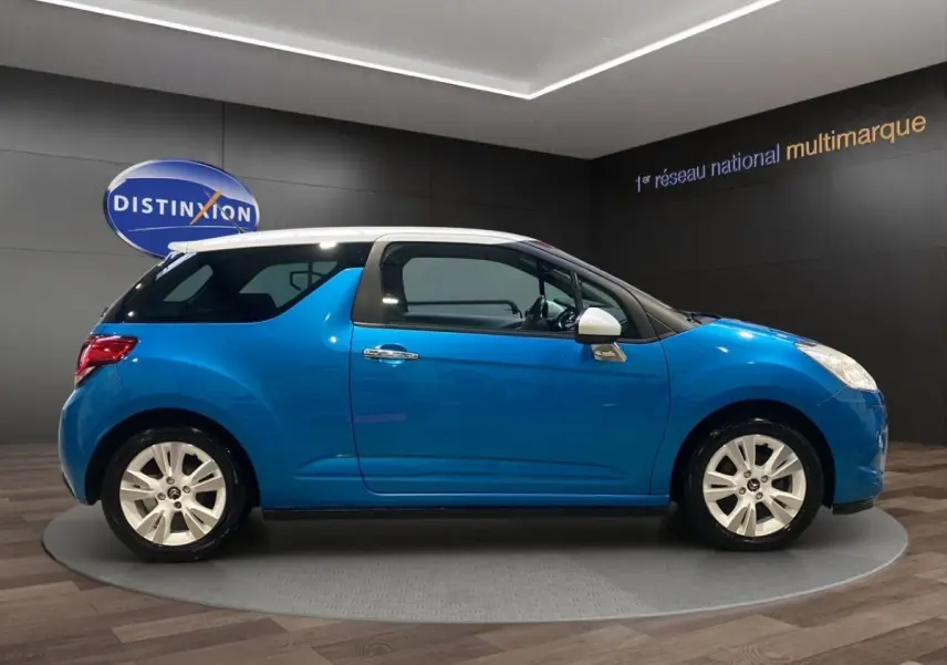 Profil droit d'une Citroën DS3 e-HDi 90 Airdream So Chic bleu avec toit blanc et jantes alliage en showroom.