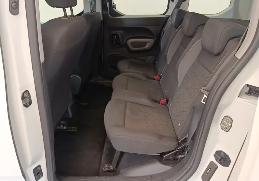 Vue intérieure côté droit sur la banquette arrière noire du Peugeot Rifter blanc, montrant les sièges 3 places et la porte ouverte.