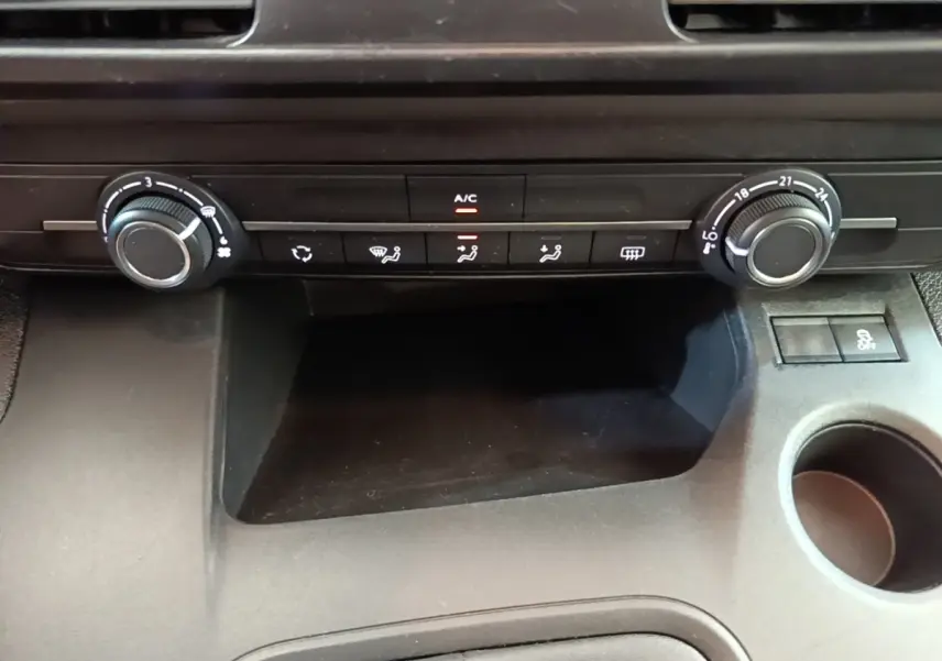 Vue rapprochée de la console centrale noire du Peugeot Rifter 2020, avec commandes de climatisation et rangement.