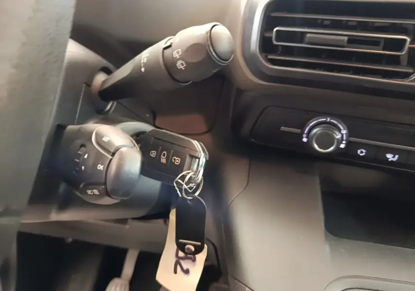 Gros plan sur la clé insérée dans le contacteur, avec commandes au volant et tableau de bord noir du Peugeot Rifter.