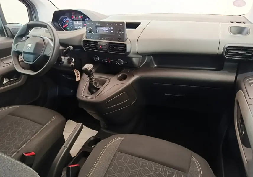 Intérieur avant du Peugeot Rifter blanc, vue côté conducteur, tableau de bord avec volant compact et levier de vitesses manuel.