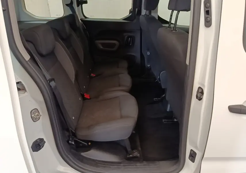 Vue intérieure côté gauche des sièges arrière noirs du Peugeot Rifter blanc, porte arrière ouverte.