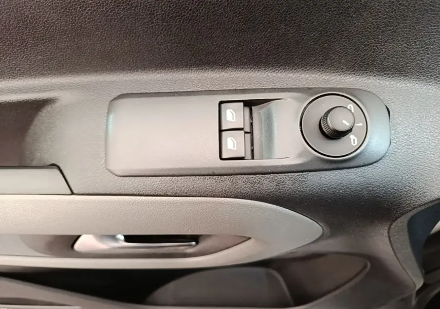 Vue rapprochée des commandes de réglage des rétroviseurs et des vitres côté conducteur d’un Peugeot Rifter blanc.