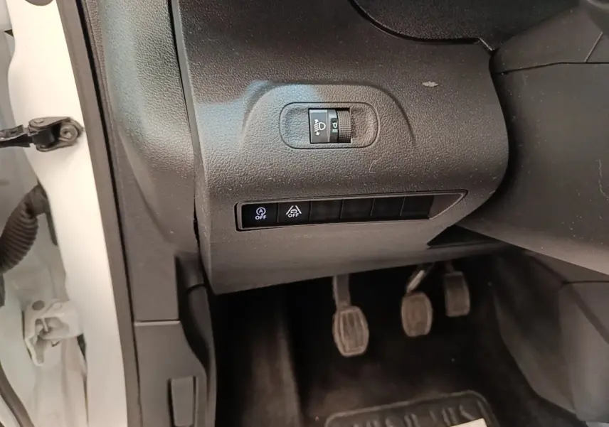 Gros plan sur les commandes d’éclairage et d’assistance côté gauche du Peugeot Rifter blanc, avec pédales manuelles visibles.