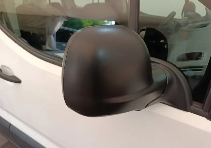 Gros plan sur le rétroviseur côté conducteur noir d’un Peugeot Rifter blanc, vue latérale gauche.