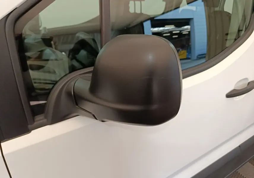 Gros plan sur le rétroviseur noir côté conducteur d’un Peugeot Rifter blanc, vue latérale gauche.