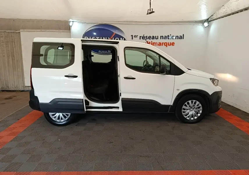 Peugeot Rifter blanc vue de profil droit avec porte coulissante arrière ouverte dans un garage.
