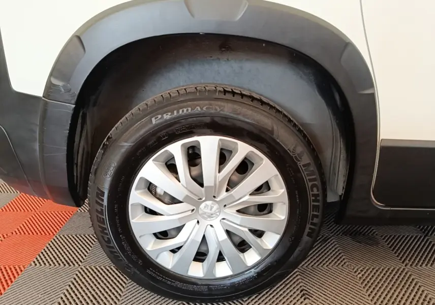 Gros plan sur la roue avant gauche d’un Peugeot Rifter blanc, avec jante argentée et pneu Michelin.