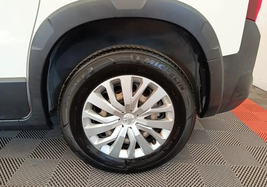 Gros plan sur la roue arrière droite d’un Peugeot Rifter blanc, mettant en valeur la jante argentée et le pneu Michelin.