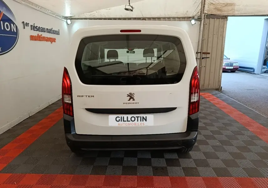 Vue arrière d'un Peugeot Rifter blanc 2020 garé en intérieur avec feux arrière verticaux rouges visibles.