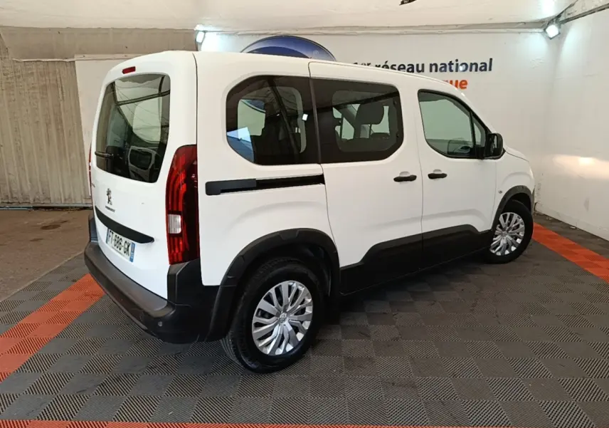 Vue 3/4 arrière droite d’un Peugeot Rifter blanc 2020 avec vitres teintées et protections noires sur les bas de caisse.
