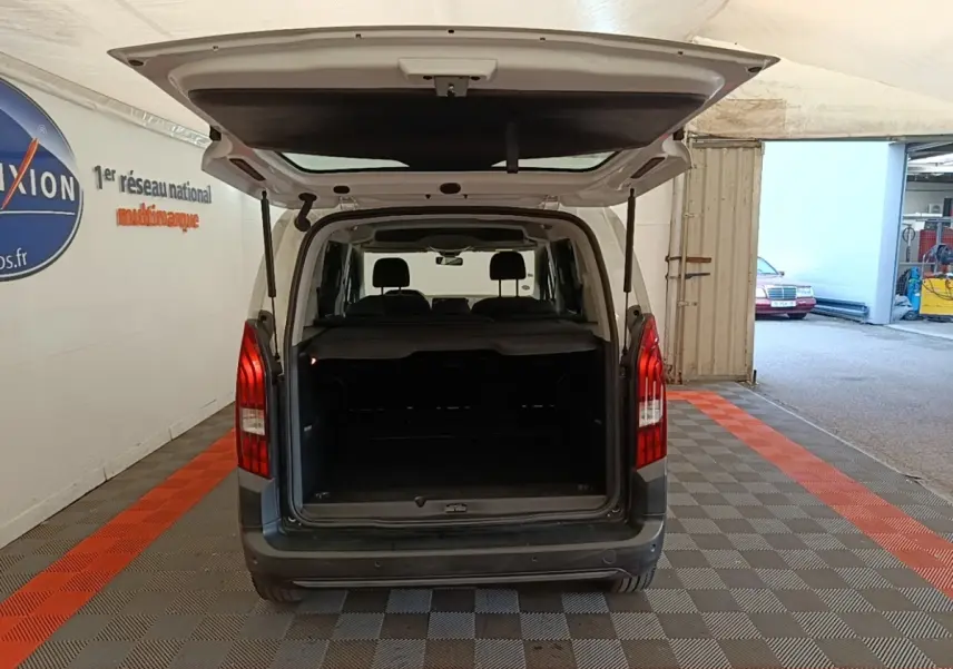Vue arrière d'un Peugeot Rifter blanc 2020 avec hayon ouvert montrant le coffre spacieux et la banquette arrière.