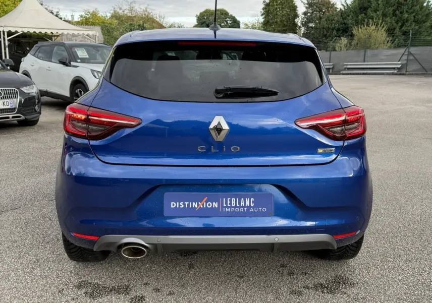 Vue arrière d'une Renault Clio RS Line bleu, avec feux LED et sortie d'échappement chromée visible à gauche.