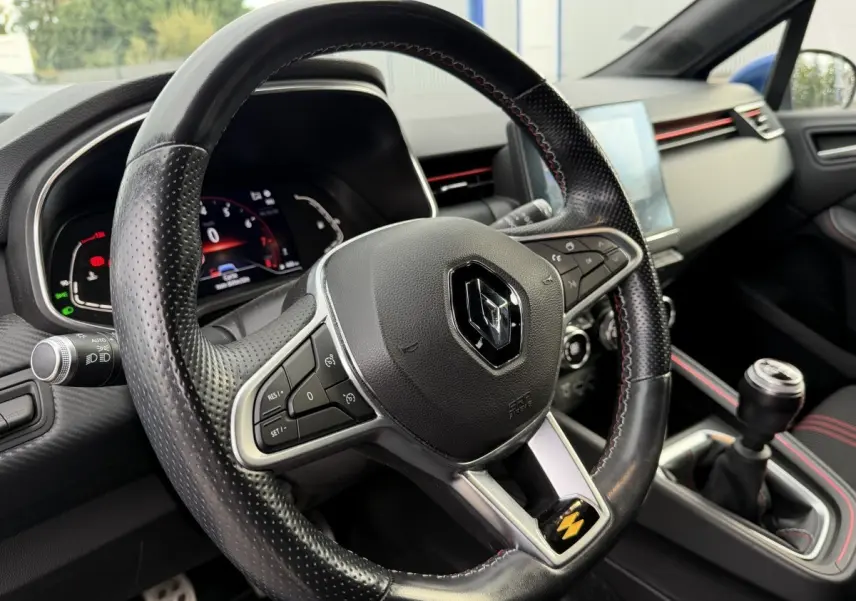Vue intérieure rapprochée du volant cuir perforé et levier de vitesse manuel de la Renault Clio RS Line bleu 2021.