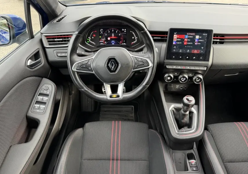 Vue intérieure avant de la Renault Clio RS Line TCe 140 2021, volant cuir, écran tactile et sièges noirs à surpiqûres rouges.