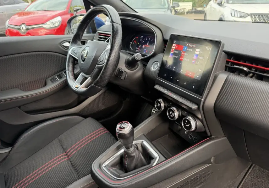 Vue intérieure côté conducteur de la Renault Clio RS Line 2021, volant cuir, écran tactile et levier de vitesses manuel.