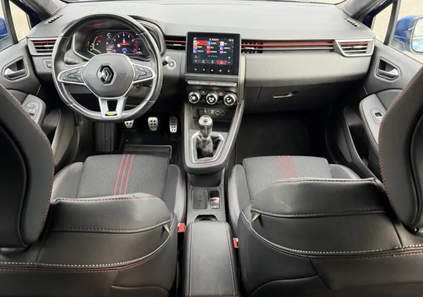 Vue intérieure avant de la Renault Clio RS Line 2021, sièges noirs avec surpiqûres rouges et volant cuir multifonction.