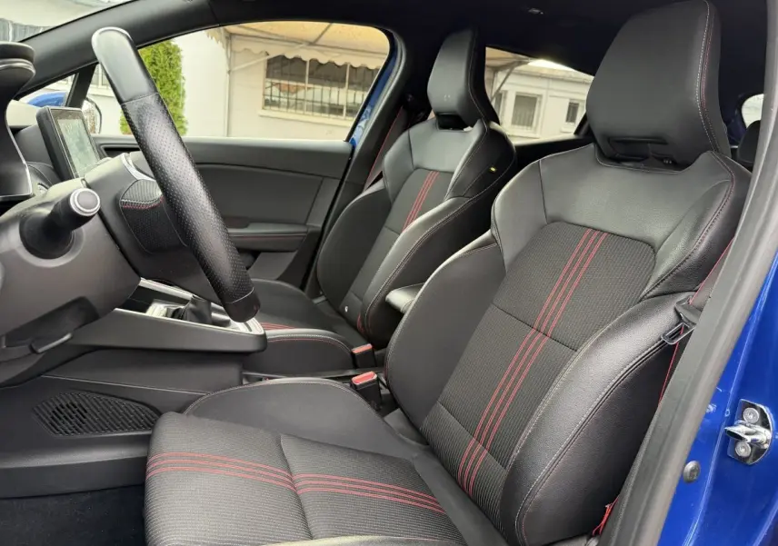 Vue intérieure côté conducteur de la Renault Clio RS Line bleu 2021, sièges sport noirs avec surpiqûres rouges.