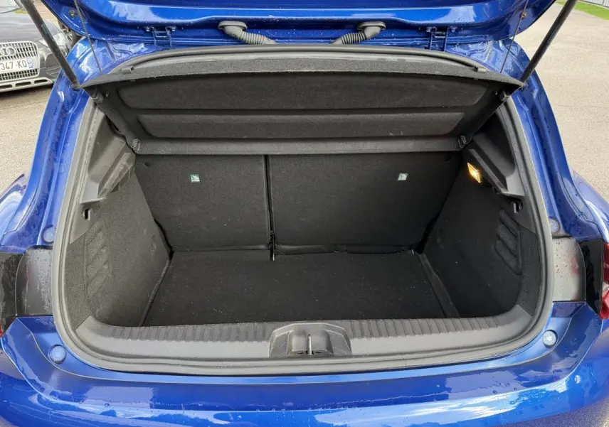 Coffre ouvert vu de l'arrière d'une Renault Clio RS Line bleu, montrant l'espace de chargement et la lumière intérieure.