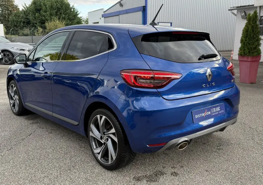 Renault Clio RS Line bleu vue 3/4 arrière droit, feux LED et jantes alliage distinctives visibles.