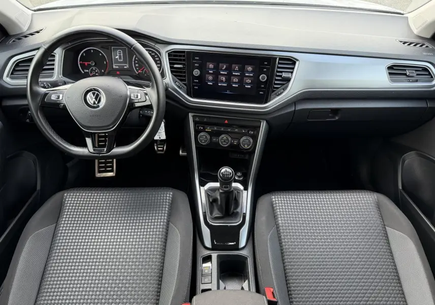 Vue intérieure du tableau de bord et console centrale du Volkswagen T-Roc 2.0 TDI avec volant cuir et levier de vitesses manuel.