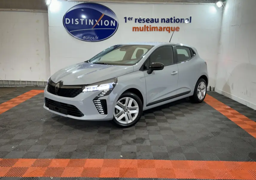 Renault Clio Evolution Blue dCi 100 gris clair vue 3/4 avant droit, feux LED allumés dans un showroom.
