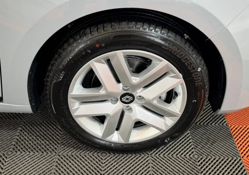 Gros plan sur la roue avant droite d'une Renault Clio gris clair, mettant en valeur la jante alliage et le pneu Bridgestone.