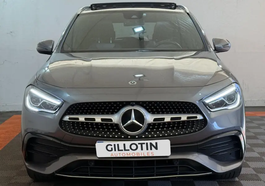 Vue frontale d'une Mercedes GLA 250 e AMG Line 2023 gris clair avec phares LED et calandre diamantée.