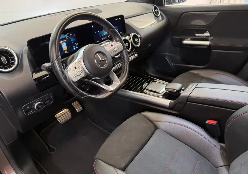 Vue intérieure côté conducteur du Mercedes GLA 250 e AMG Line 2023, avec volant cuir noir et écran tactile double.
