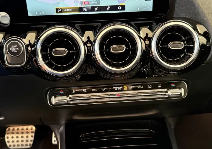 Vue rapprochée du tableau de bord noir du Mercedes GLA 250 e AMG Line 2023, avec aérateurs ronds chromés et écran tactile.