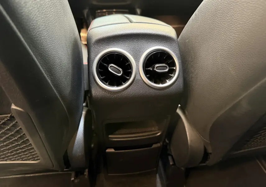 Vue rapprochée des aérateurs arrière noirs et chromés entre les sièges avant d’un Mercedes GLA 250 e AMG Line gris clair.