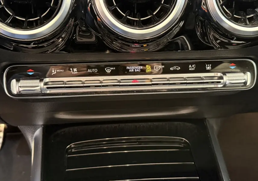 Détail du tableau de bord noir avec commandes climatisation et aérateurs ronds chromés d'une Mercedes GLA 250 e AMG Line 2023.