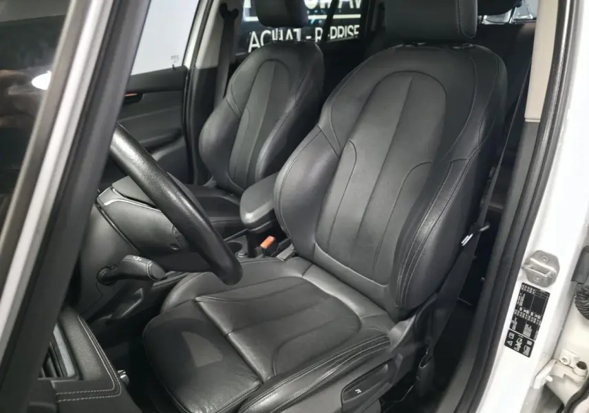 Vue intérieure côté conducteur de la BMW Série 2 Gran Tourer 218d xDrive blanche avec sièges en cuir noir.