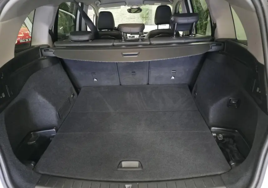 Vue arrière du coffre spacieux et plat de la BMW Série 2 Gran Tourer 218d xDrive blanc, avec banquette arrière rabattue.
