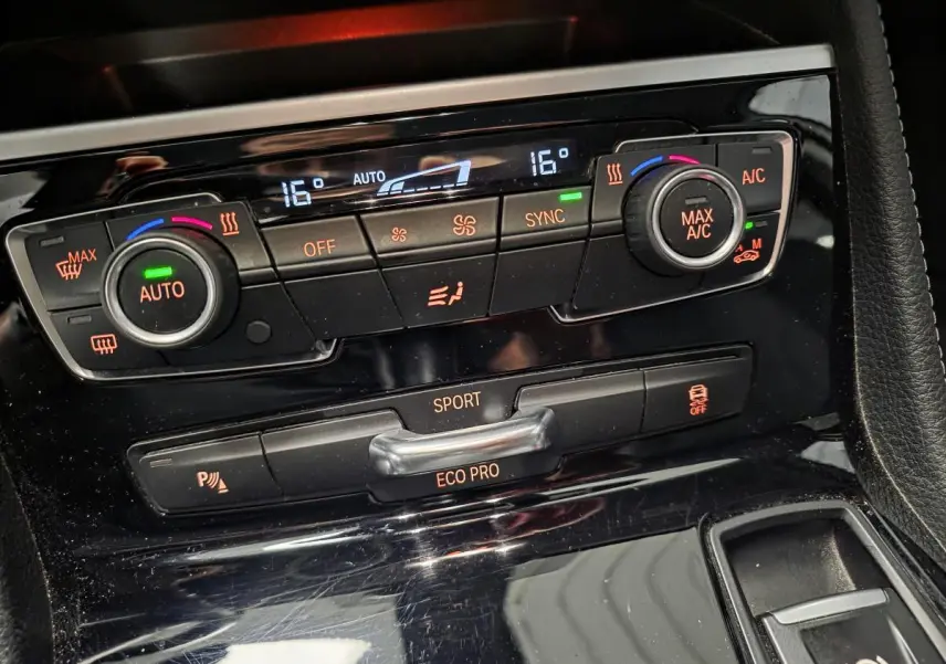 Détail de la console centrale noire brillante avec commandes de climatisation et modes de conduite BMW Série 2 Gran Tourer.