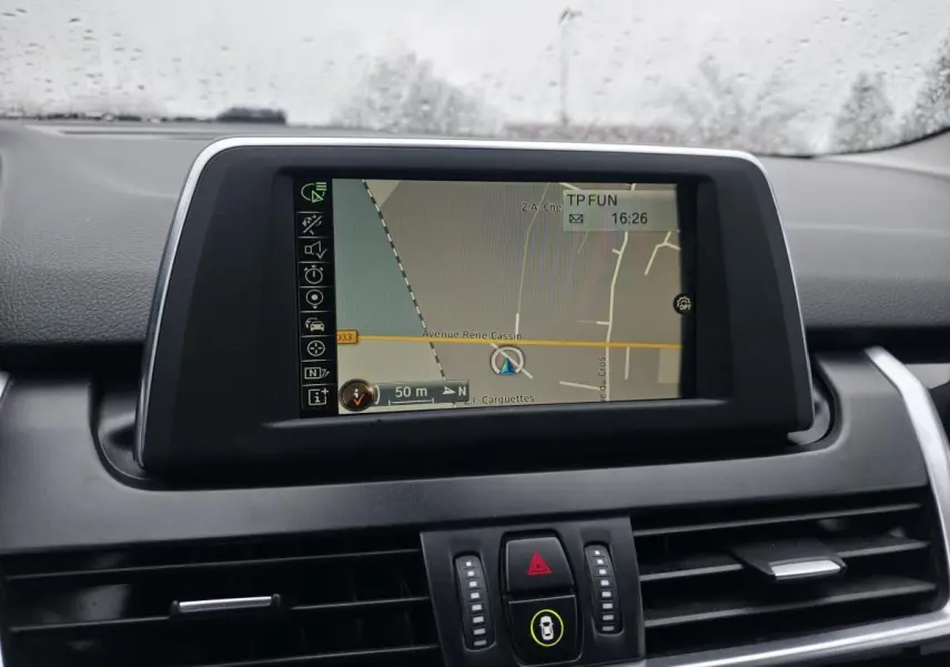 Écran central de navigation couleur dans le tableau de bord noir d'une BMW Série 2 Gran Tourer 218d blanc.