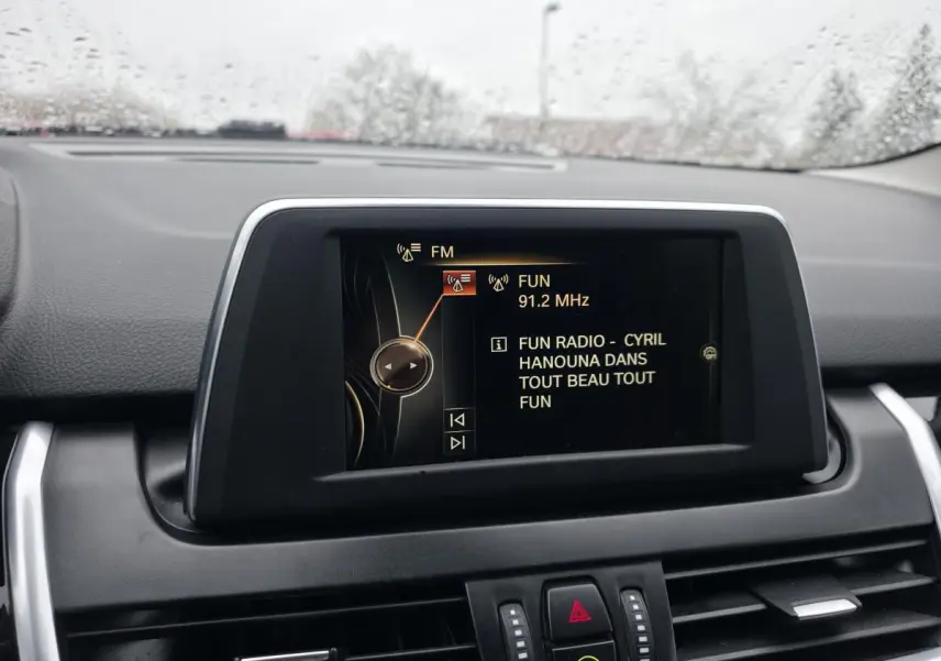 Écran central de bord affichant la radio FM dans l’habitacle d’une BMW Série 2 Gran Tourer blanche.