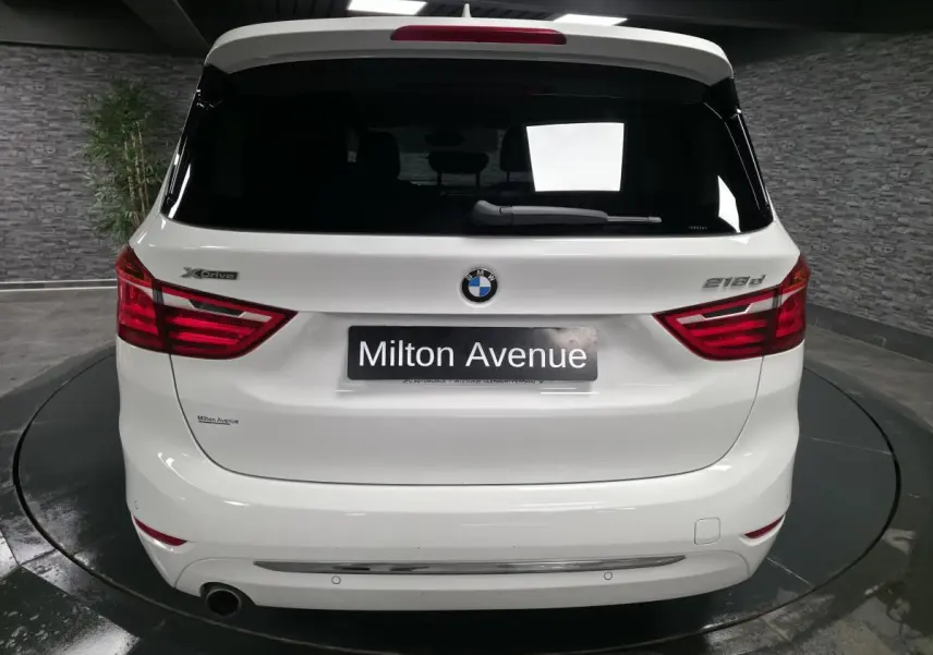 Vue arrière d'une BMW Série 2 Gran Tourer blanche avec badge xDrive et modèle 218d visible sur le hayon.