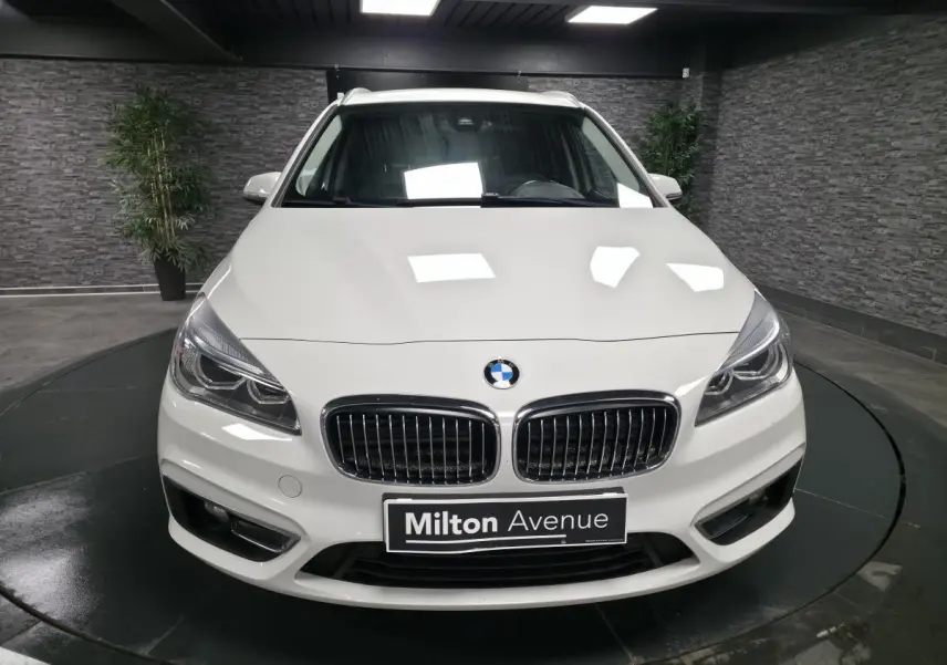 Vue avant d'une BMW Série 2 Gran Tourer blanche avec calandre chromée et phares LED dans un showroom.
