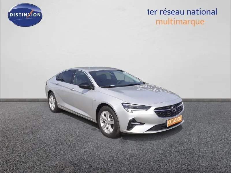 Opel Insignia Grand Sport gris clair vue 3/4 avant droit, calandre noire et jantes alliage visibles.