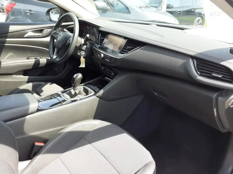 Vue intérieure côté conducteur de l'Opel Insignia Grand Sport gris clair 2021, avec tableau de bord et console centrale visibles.