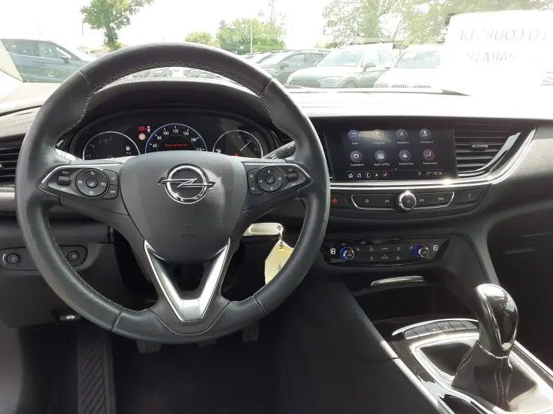 Vue intérieure centrée sur le volant noir de l'Opel Insignia Grand Sport 2021 avec tableau de bord et écran tactile.